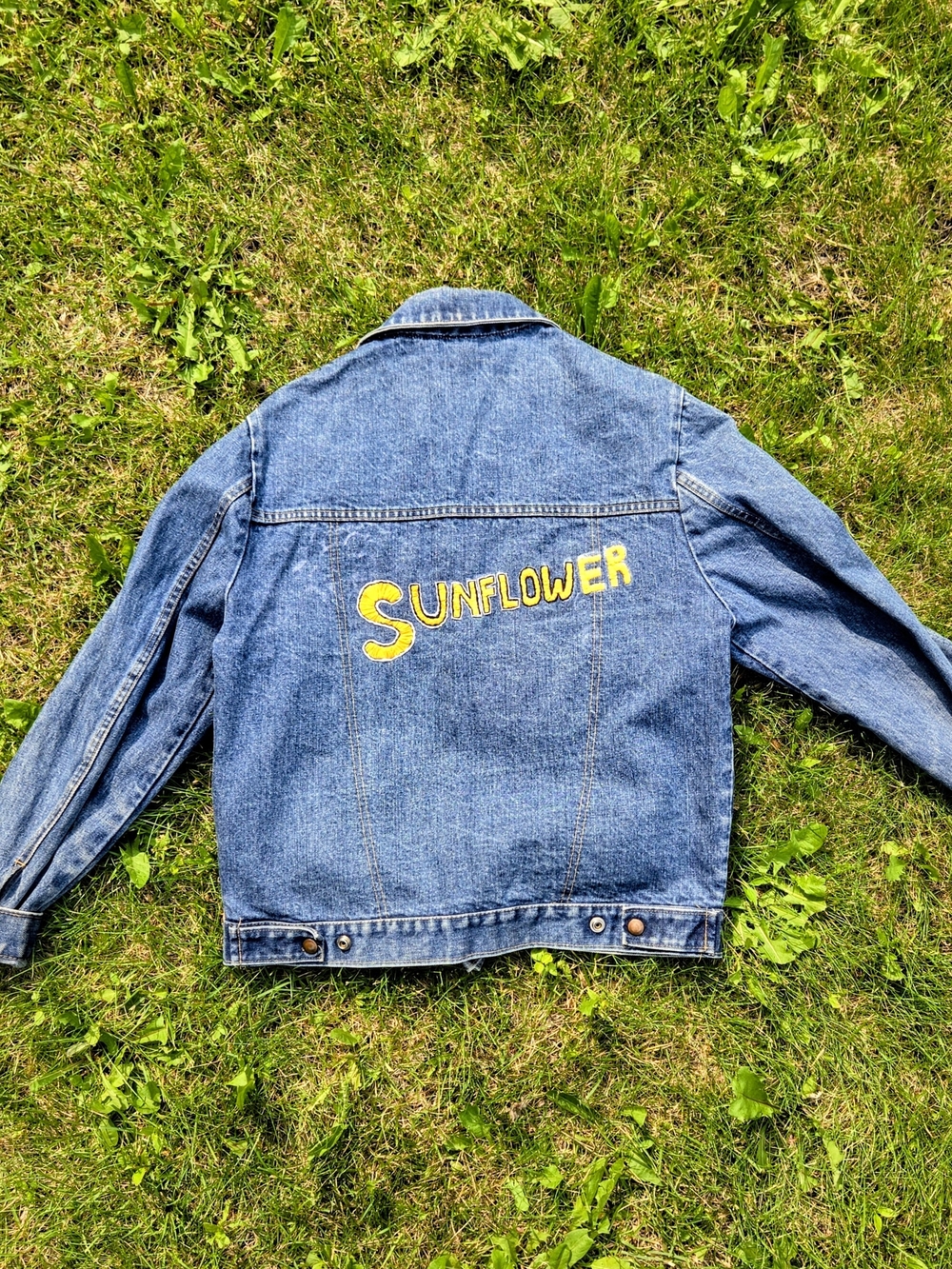 Olympia Activewear Blue Denim Jacket with Yellow Sunflower Lettering